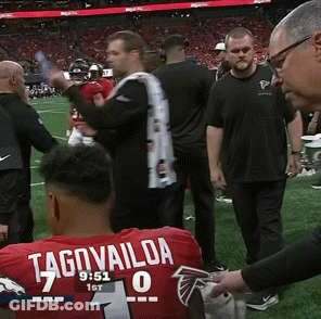 Man In Red Tagovailoa Jersey Sitting On Football Field GIF