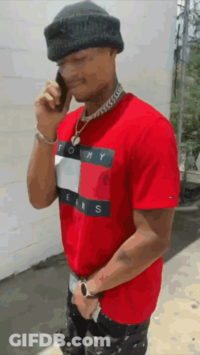 Man In Red Tommy Jeans Shirt Talking On Cell Phone GIF