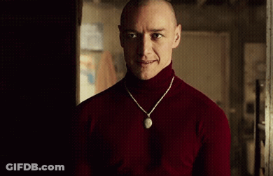 Man In Red Turtleneck And Necklace In Dark Room GIF
