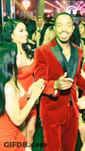 Man In Red Tuxedo Dancing With Two Women In Red Dresses GIF