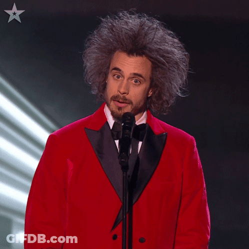 Man In Red Tuxedo Speaking Into Microphone GIF