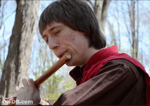 Man In Red Vest Playing Flute In Woods GIF