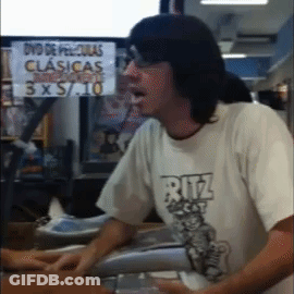 Man In Ritz Shirt Standing In Front Of DVD De Peliculas Clasicas 3X5 10 Sign GIF