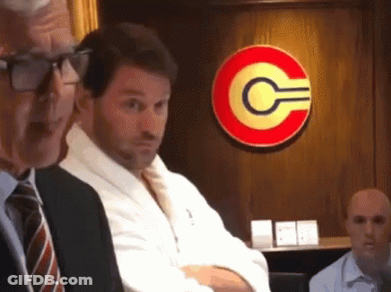 Man In Robe Sitting In Front Of Sign With C GIF