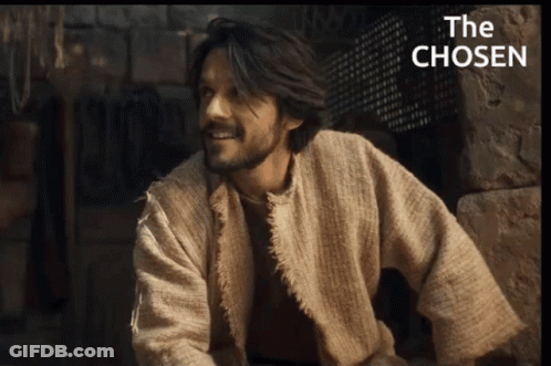 Man In Robe Smiling In Front Of The Chosen Sign GIF