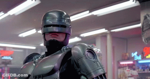 Man In Robot Costume In Front Of Bull Sign GIF
