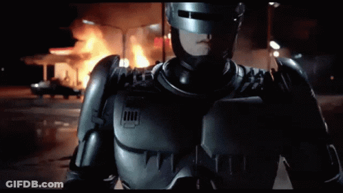 Man In Robot Costume In Front Of Fire GIF