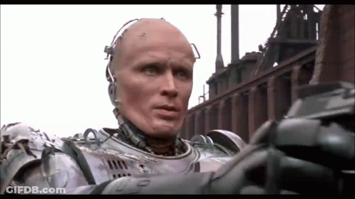 Man In Robot Suit In Front Of Factory GIF