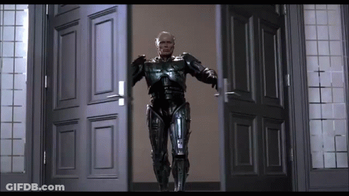 Man In Robot Suit Standing In Doorway With Arms Outstretched GIF