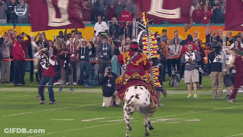 Man In Roman Helmet Holding Sword In Front Of Suited Man GIF