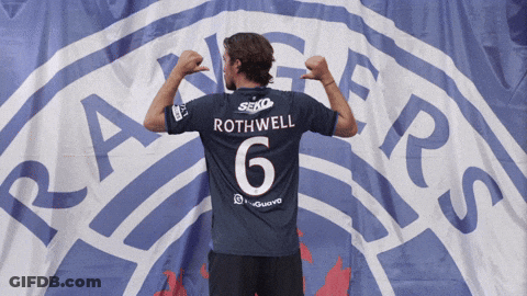 Man In Rothwell Jersey In Front Of Rangers Logo GIF