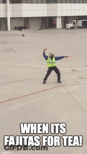 Man In Safety Vest Jumping With Sign Saying When It's Fajitas For Tea GIF