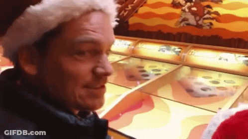 Man In Santa Hat Playing Game At Amusement Park GIF