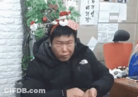 Man In Santa Headband By Christmas Tree GIF