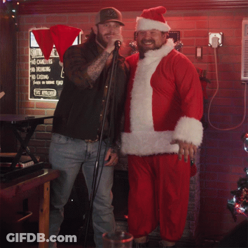 Man In Santa Suit Next To Man Singing GIF