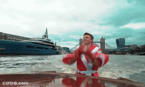 Man In Santa Suit Riding Boat GIF