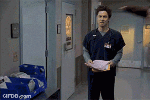 Man In Scrub Top Holding Paper At Surgical Room Door GIF