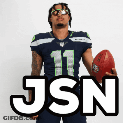 Man In Seahawks Jersey Holding Football In Front Of JSON Sign GIF