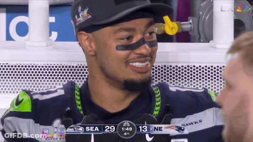 Man In Seahawks Uniform Smiling In Front Of 1:49 Scoreboard GIF