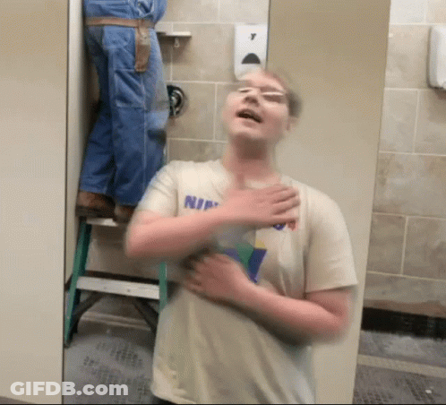 Man In Shirt Saying Nin Standing In Bathroom GIF