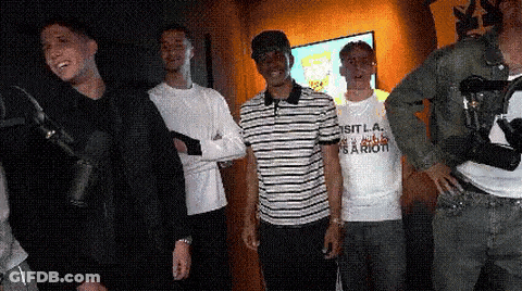 Man In Shirt Saying Sit La Standing Next To Another Man GIF