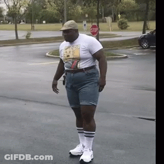 Man In Shorts And T-Shirt With Stop Sign GIF