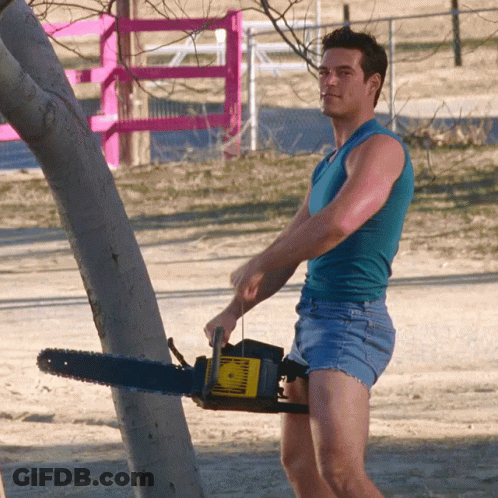 Man In Shorts Holding Chainsaw GIF