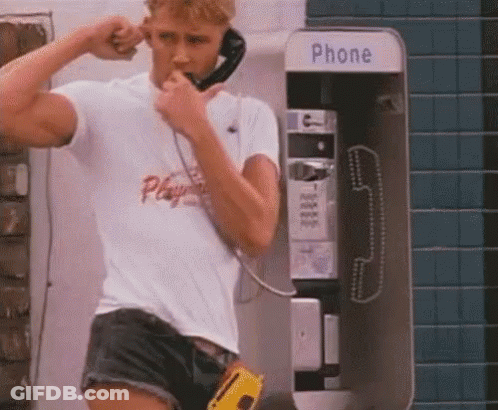 Man In Shorts Talking On Payphone GIF