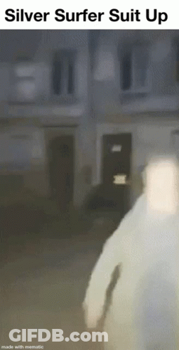 Man In Silver Surfer Suit Walking In Front Of Building GIF