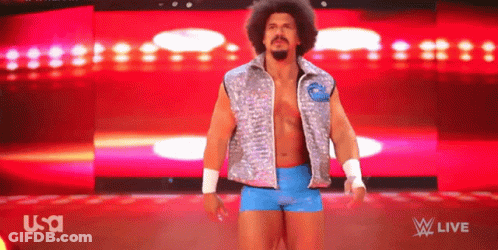Man In Silver Vest And Blue Shorts In Front Of USA Background GIF