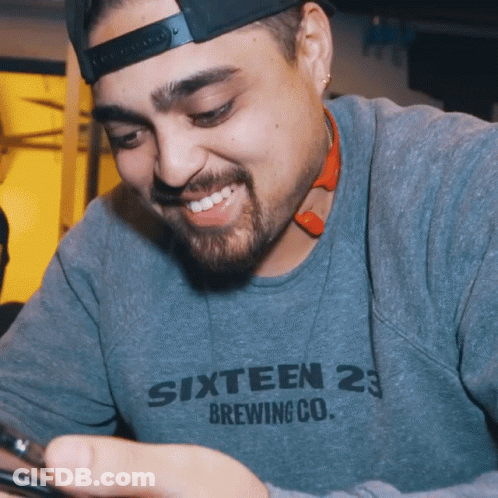 Man In Sixteen 23 Brewing Co Sweatshirt Looking At Phone GIF