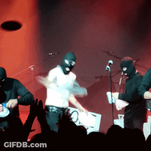 Man In Ski Mask Playing Drums On Stage GIF