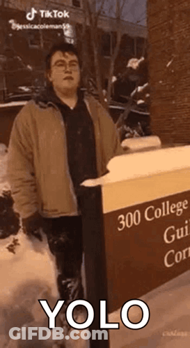 Man In Snow Next To YOLO Sign GIF