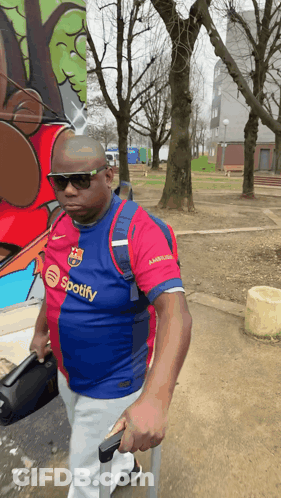 Man In Spotify Shirt Walking With Suitcase GIF