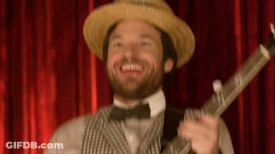 Man In Straw Hat And Bow Tie Holding Guitar In Front Of Red Curtain GIF