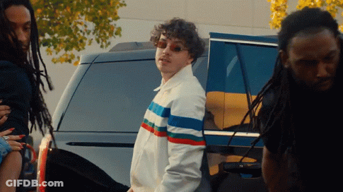 Man In Striped Jacket In Front Of SUV GIF