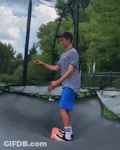 Man In Striped Shirt, Blue Shorts, And Nike Shoes On Trampoline GIF