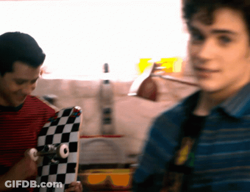 Man In Striped Shirt Holding Checkered Skateboard GIF