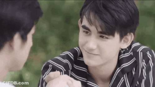 Man In Striped Shirt Holding Hand And Smiling GIF