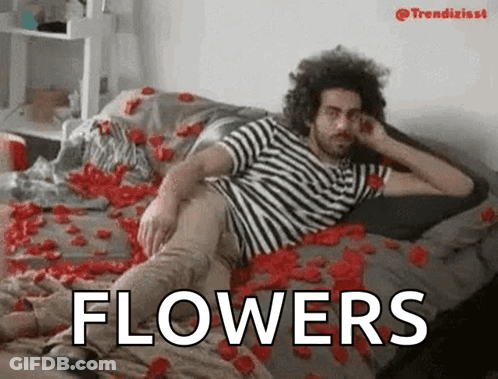 Man In Striped Shirt Laying On Rose Petals With Word Flowers GIF