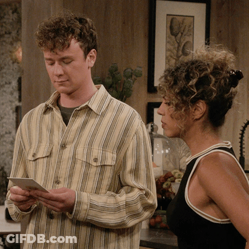 Man In Striped Shirt Looking At Paper Next To Woman GIF