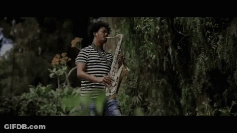 Man In Striped Shirt Playing Saxophone Outside GIF