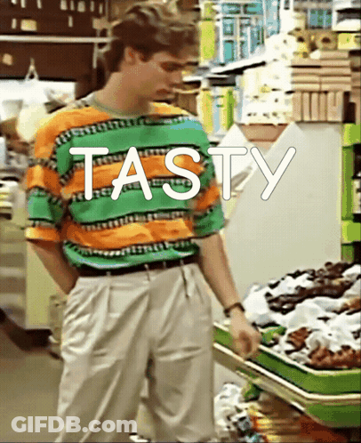 Man In Striped Shirt Standing In Front Of Shelf Saying Tasty GIF