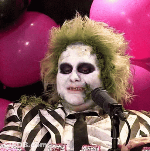 Man In Striped Shirt Talking Into Microphone With Pink Balloons GIF
