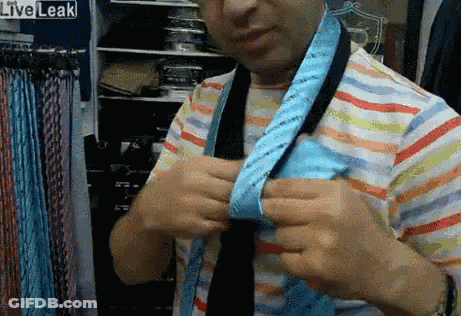Man In Striped Shirt Tying Blue Tie In Front Of Liveleak Sign GIF