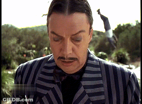 Man In Striped Suit With Mustache Looking Down GIF