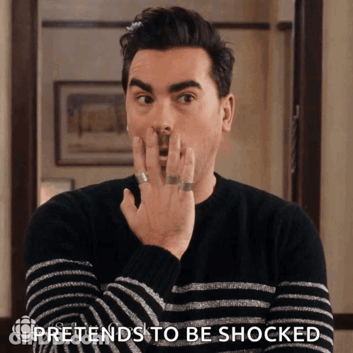 Man In Striped Sweater Pretends Shocked Covering Mouth GIF