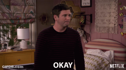 Man In Striped Sweater Saying Okay In Bedroom GIF