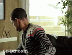 Man In Striped Sweater Sitting On Couch GIF
