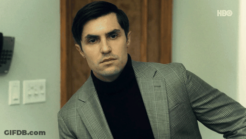 Man In Suit And Black Turtleneck In Front Of HBO Wall GIF